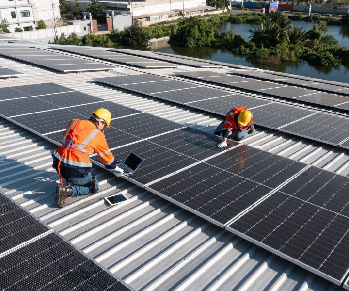 Two men are installing solar panels on the roof of a building.