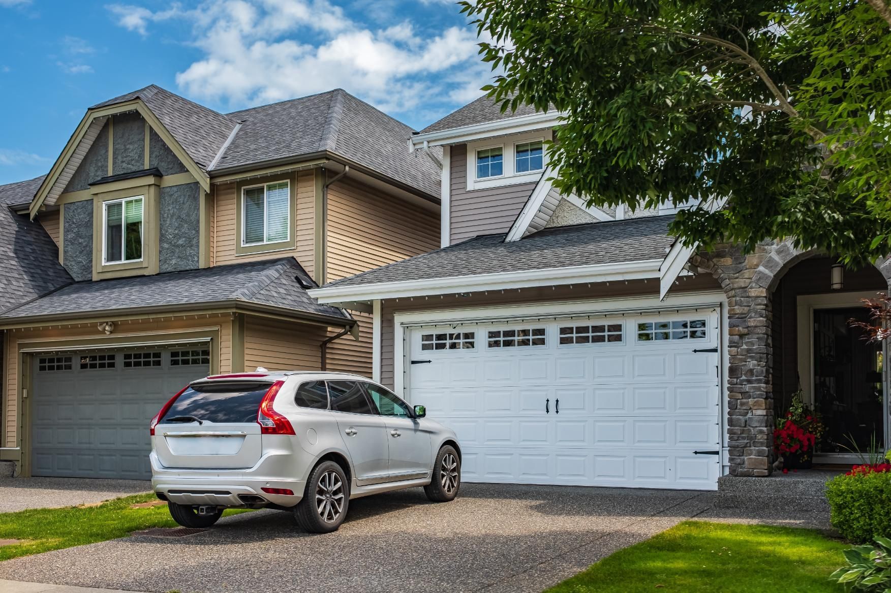 A white car is parked in front of a large house.