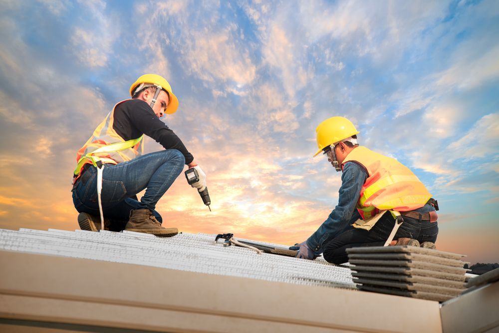 Two construction workers are working on the roof of a building.