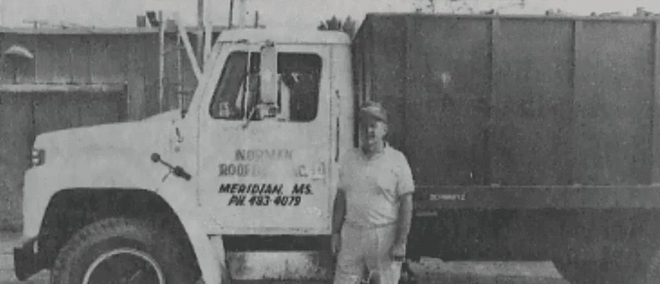 a man is standing in front of a dump truck in a black and white photo .