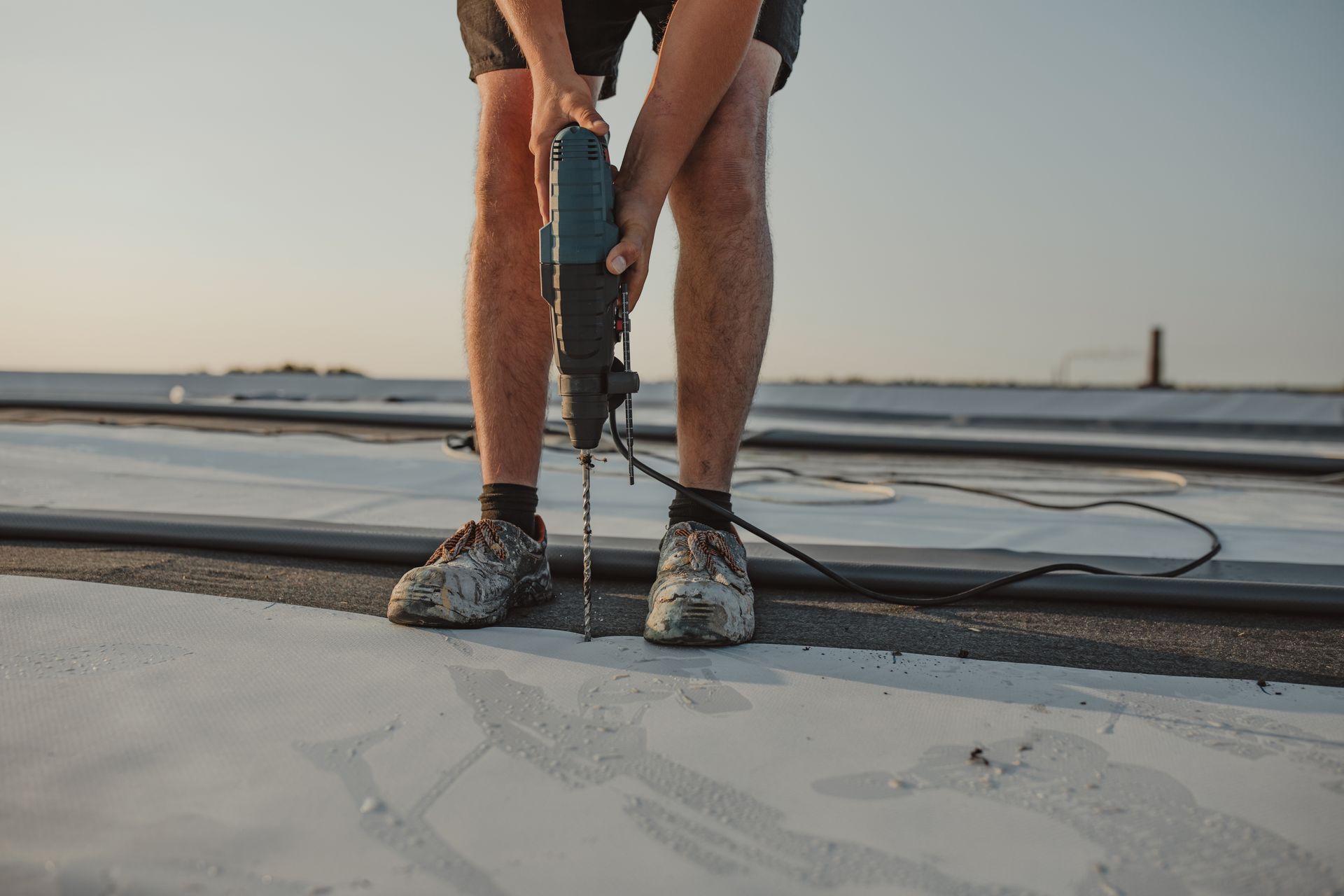 A man is using a drill on a roof.