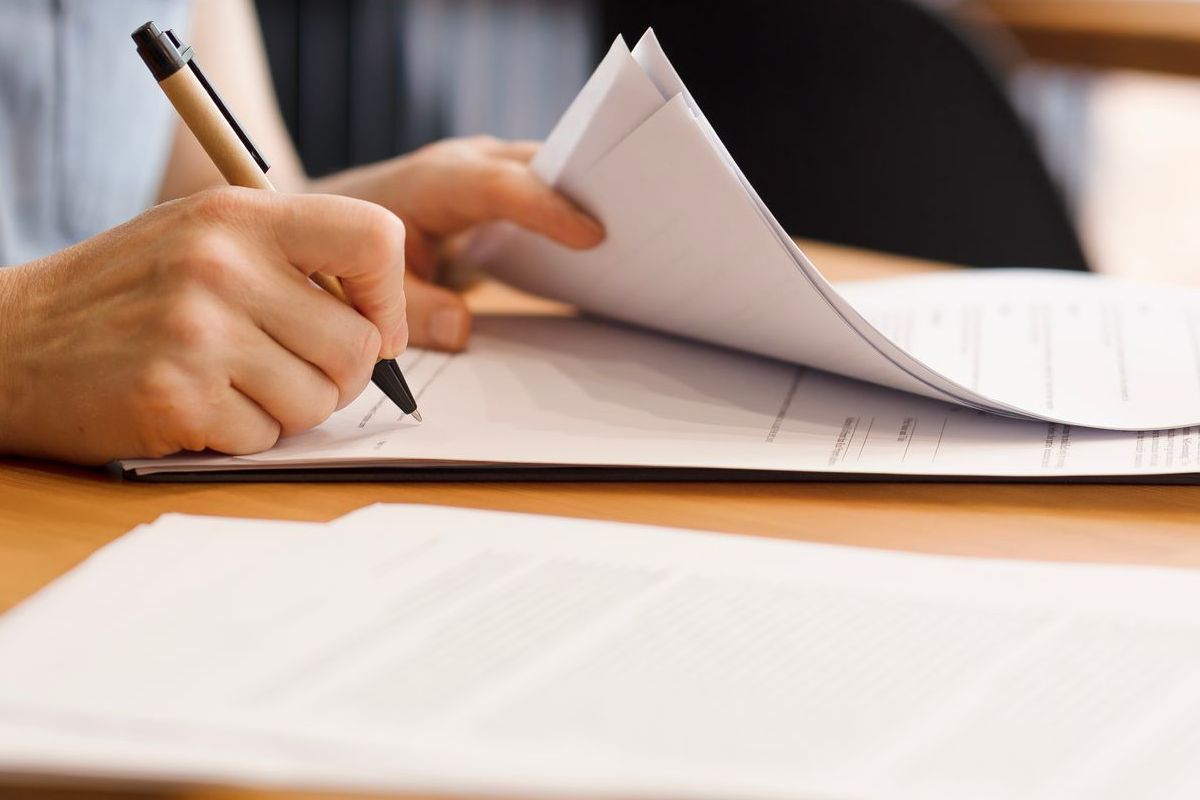 A person is writing on a piece of paper with a pen.