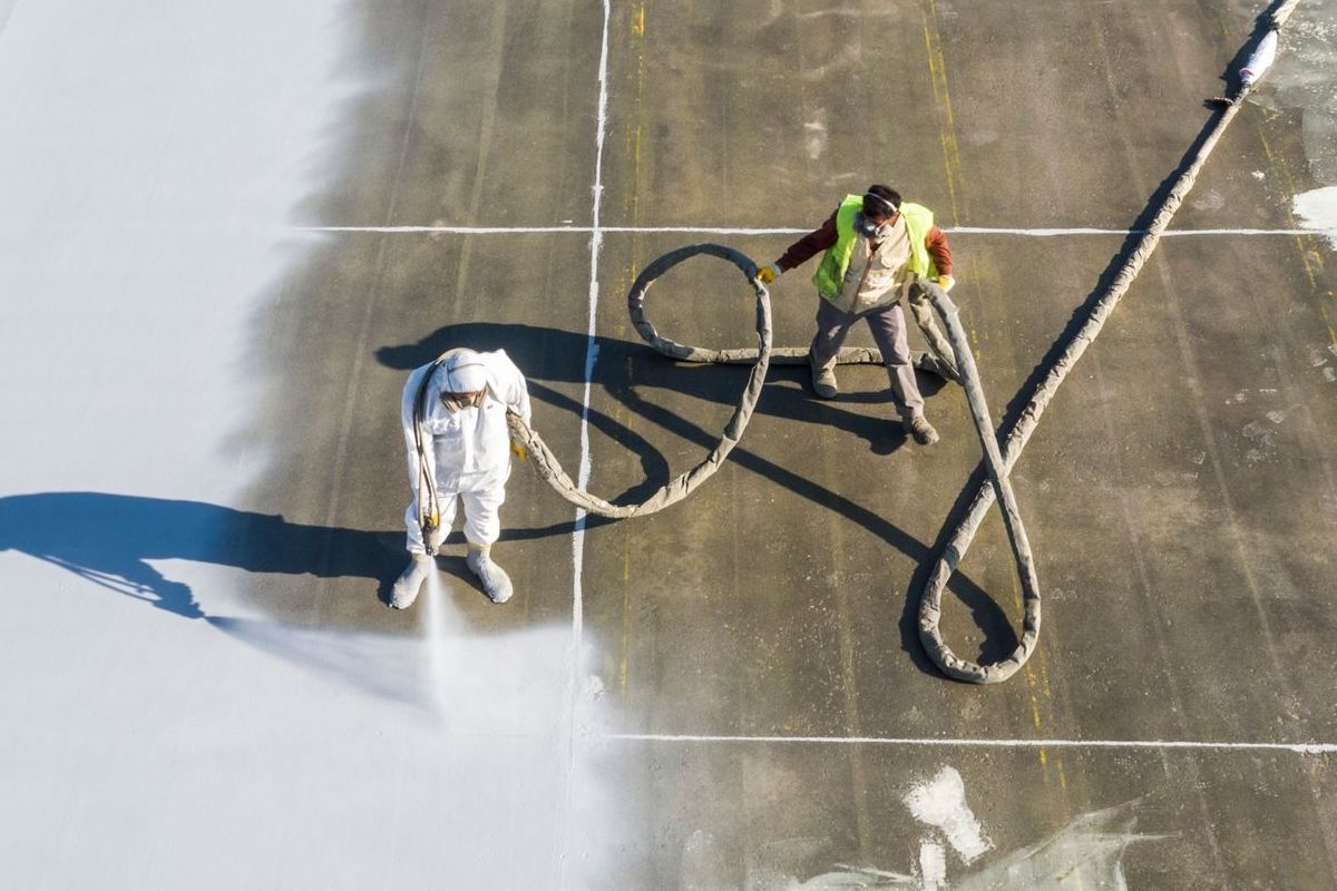 Two men are spraying a roof with a hose.