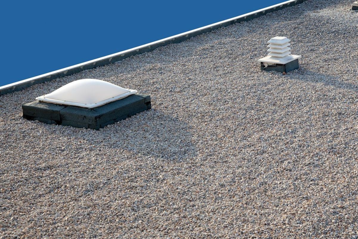 A roof with three skylights on it and a blue sky in the background