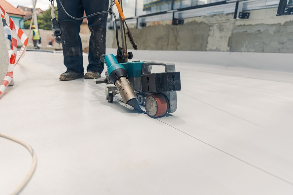 A man is using a machine to seal a roof.