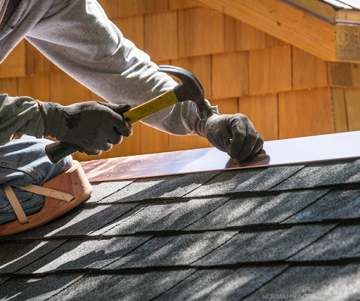 A man is working on a roof with a hammer