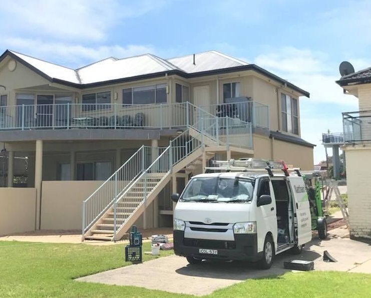 A paint roller applying white paint to a concrete wall, leaving a painted stripe.