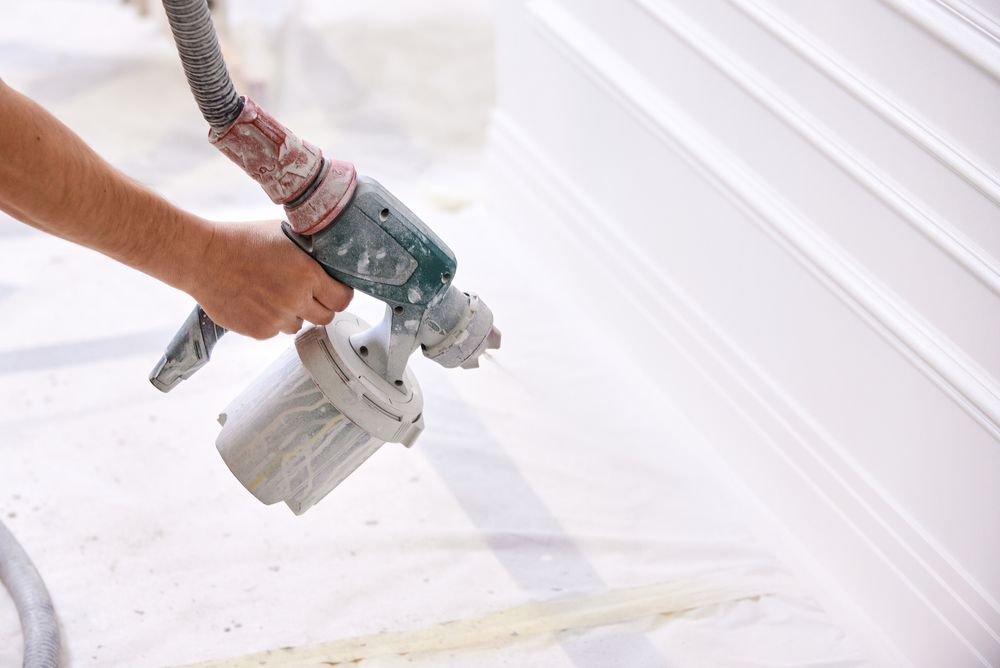 A paint roller applying white paint to a concrete wall, leaving a painted stripe.