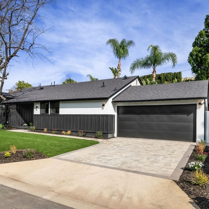 A paint roller applying white paint to a concrete wall, leaving a painted stripe.