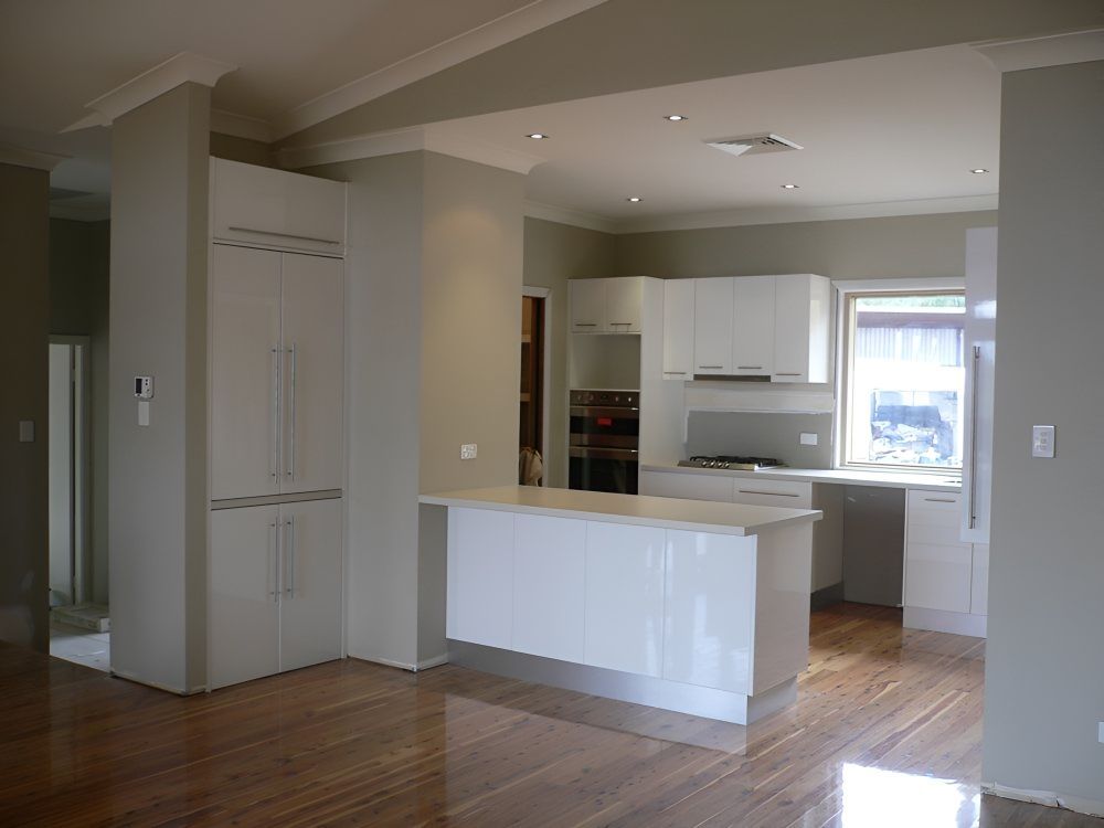 An Empty Kitchen With White Cabinets And Hardwood Floors — Gavin Cummings Kitchens in Condobolin, NSW