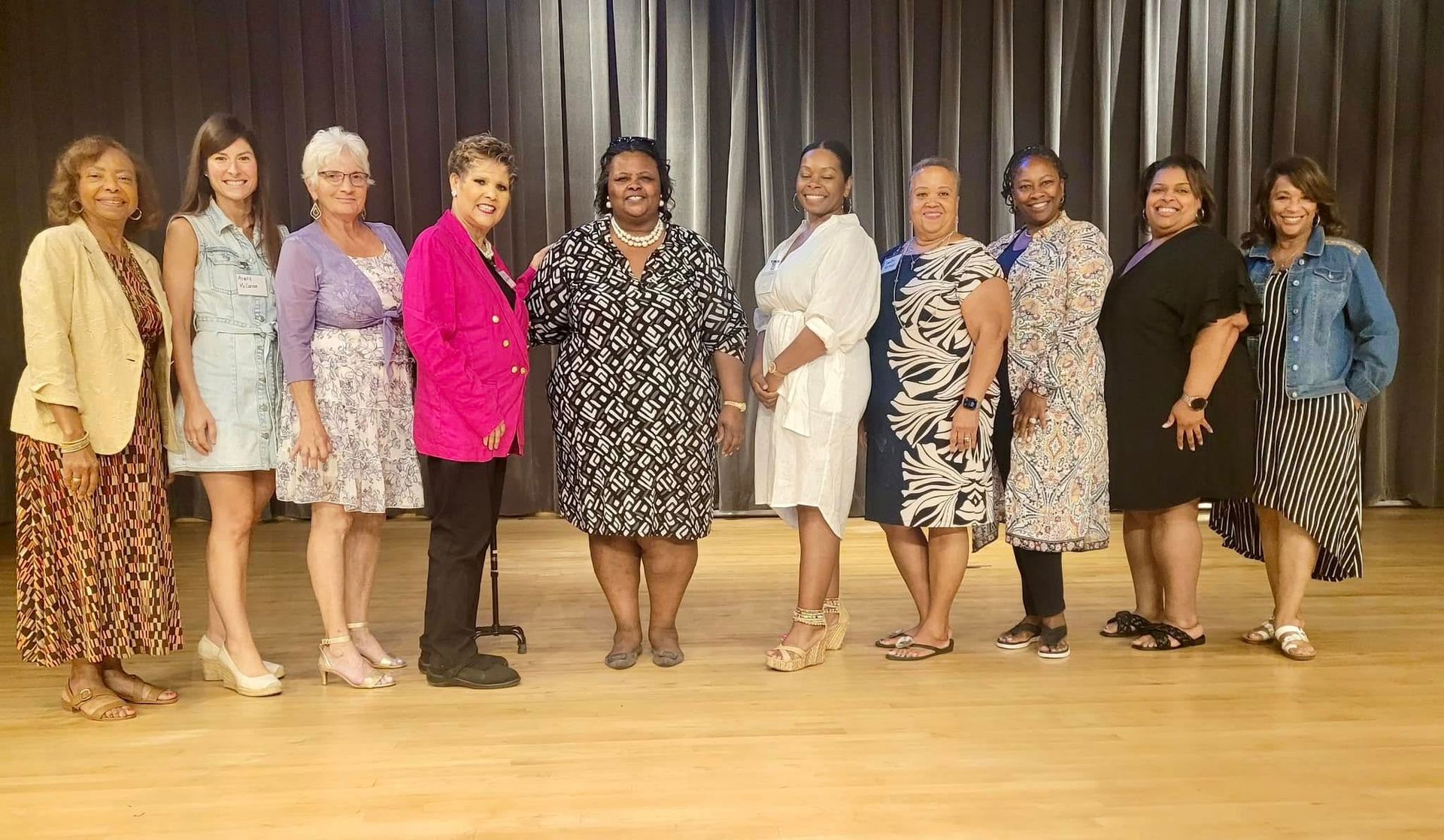 Group of ten people standing on a stage, posing for a photo.