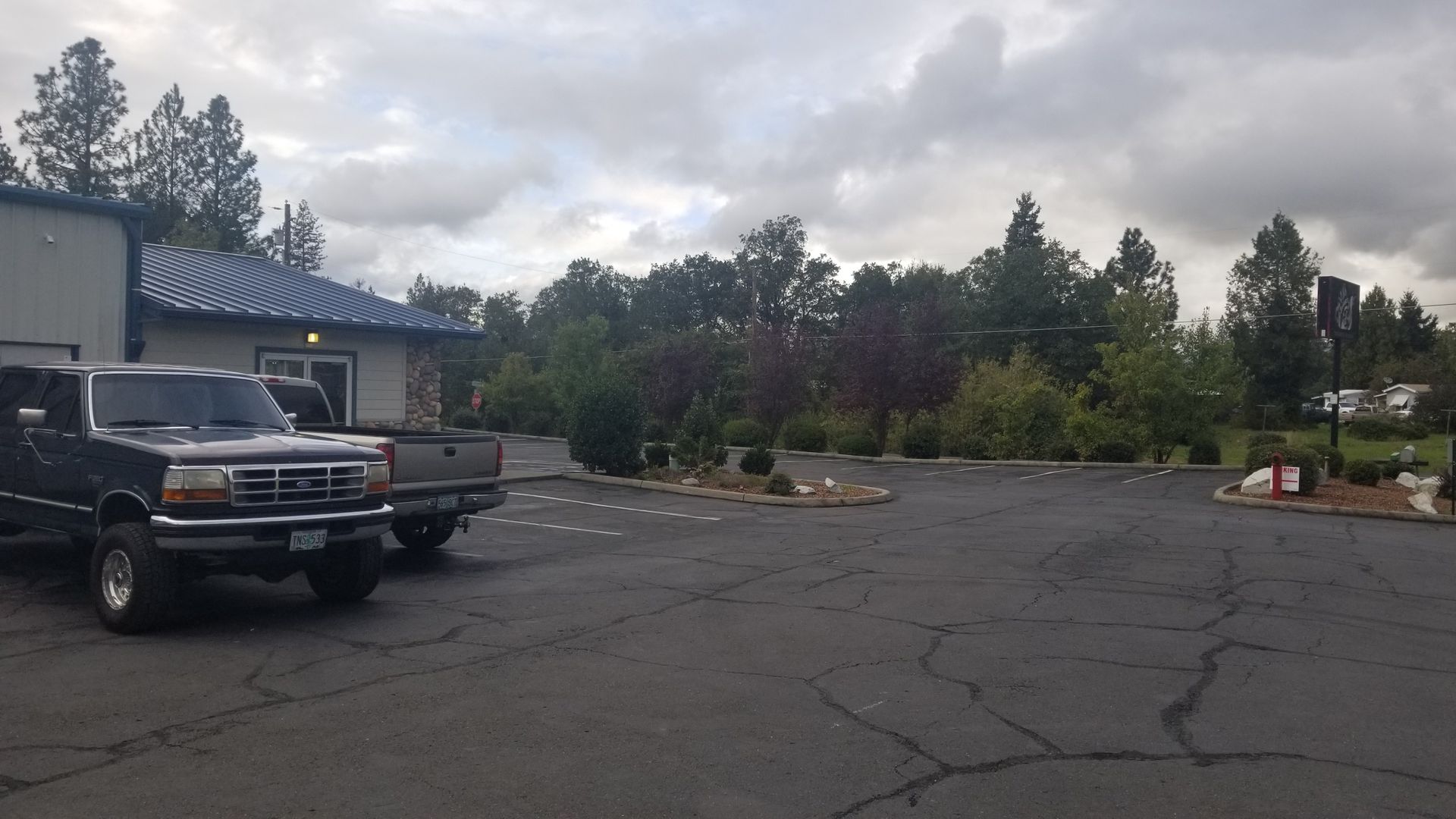 Two trucks are parked in a parking lot in front of a building