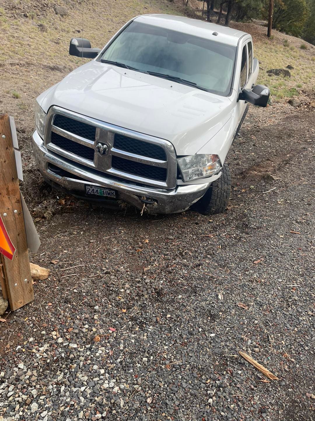 A white truck is sitting on top of a gravel road.