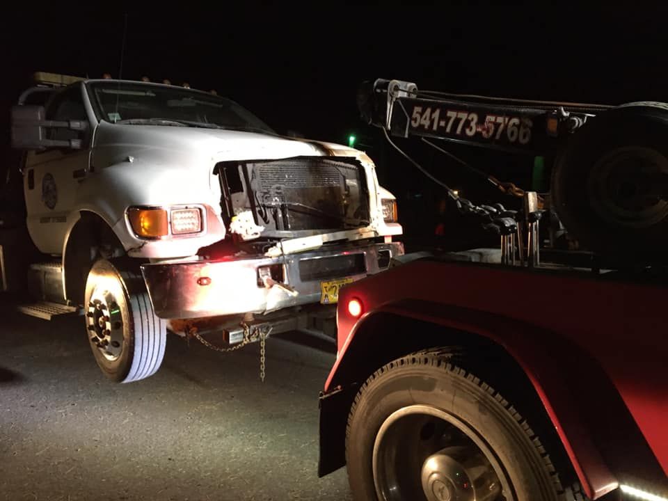 A white truck is being towed by a red tow truck