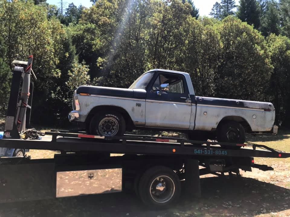 A white truck is sitting on top of a tow truck.