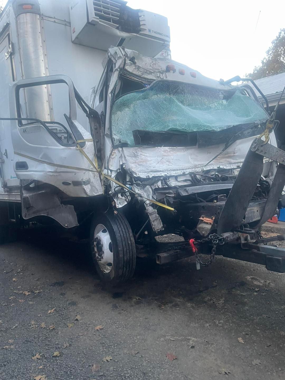 A truck with a broken windshield is sitting on the side of the road.