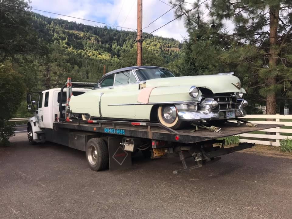 An old car is being towed by a tow truck.