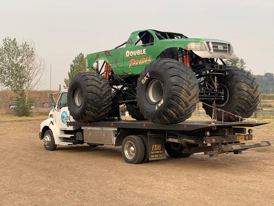 A monster truck is being towed by a tow truck.