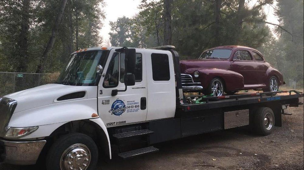 A white tow truck with a red car on the back