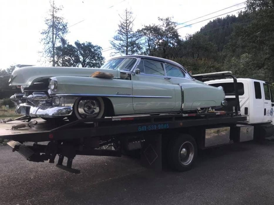 An old car is being towed by a tow truck.