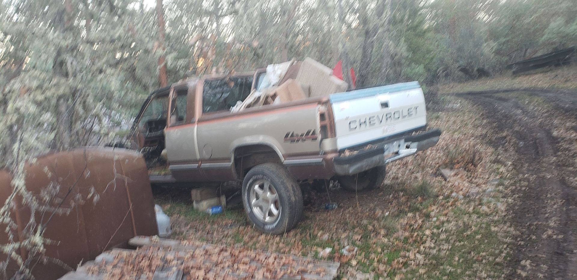 A chevrolet truck is sitting on the side of a dirt road.