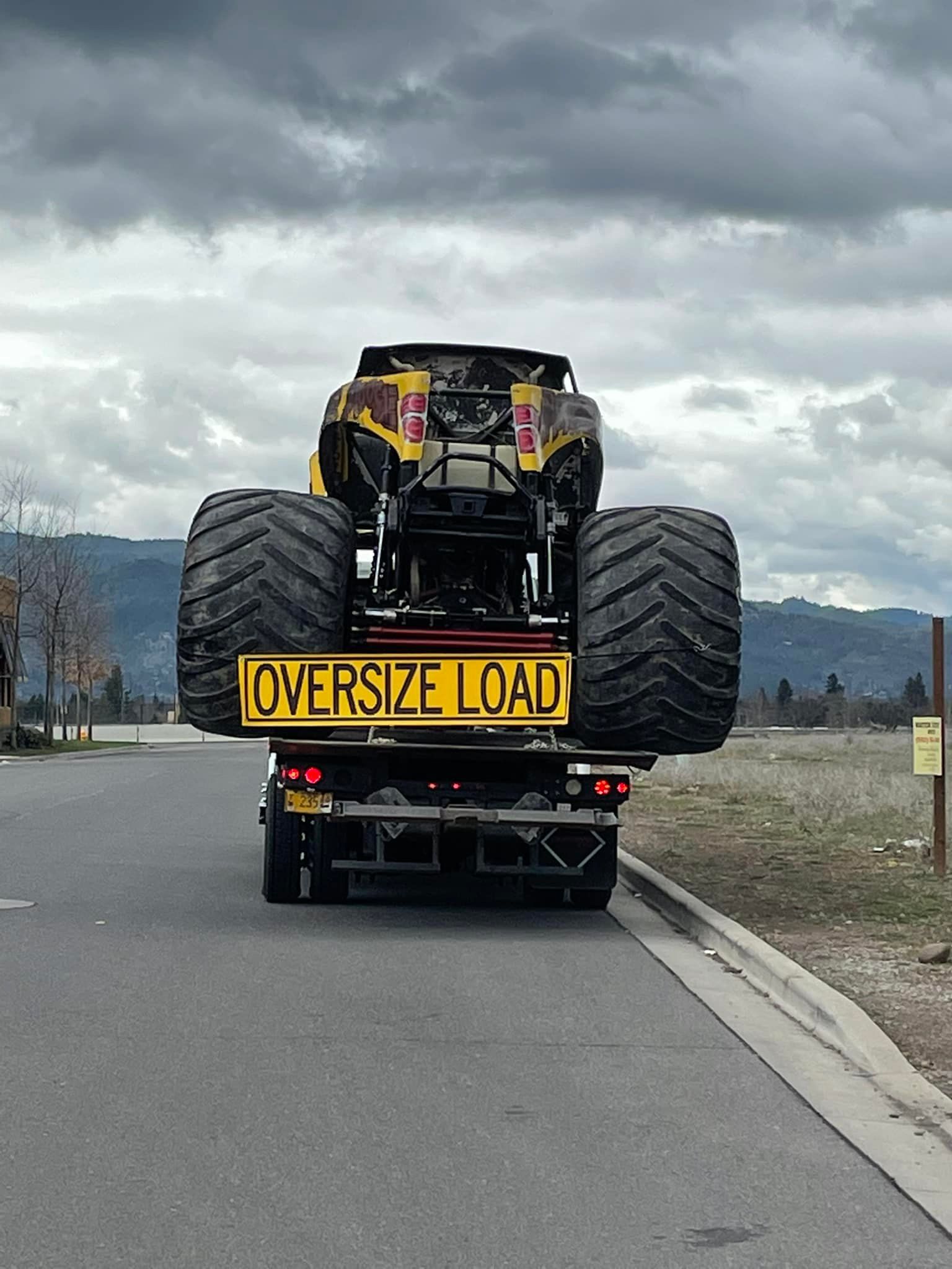 An atv is being towed by a truck that says oversized load
