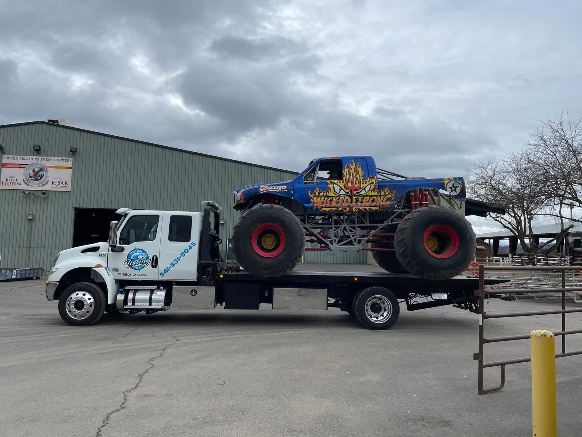 A monster truck is being towed by a tow truck.