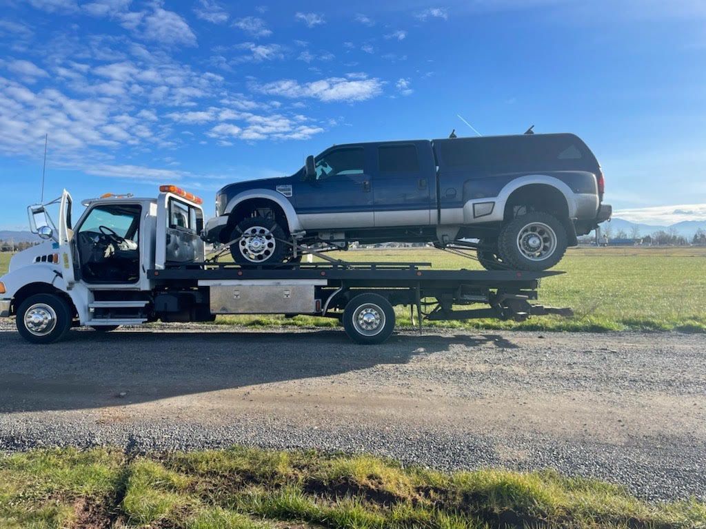 A tow truck is towing a pickup truck and a suv.