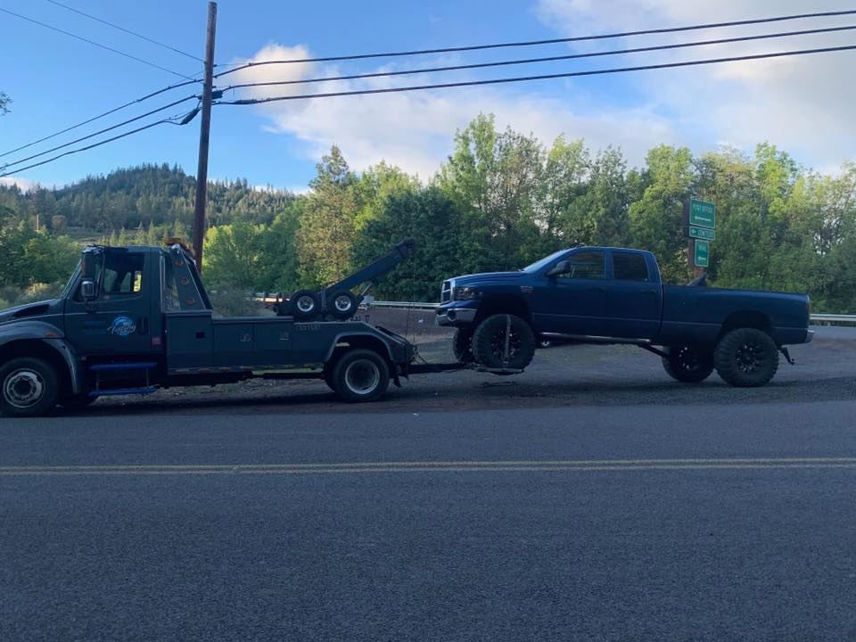 A tow truck is towing a truck down the road.