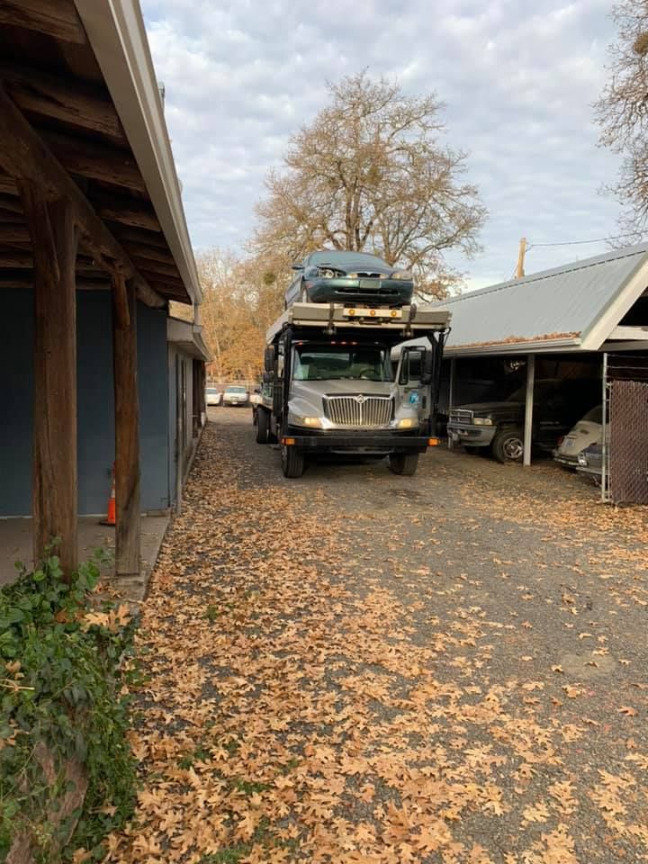 A garbage truck is parked in a parking lot filled with leaves.