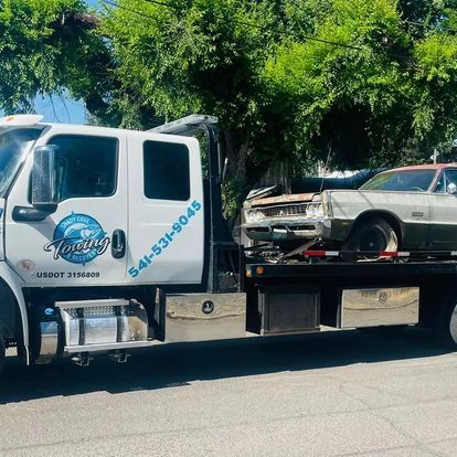 A tow truck is carrying a car on the back of it.