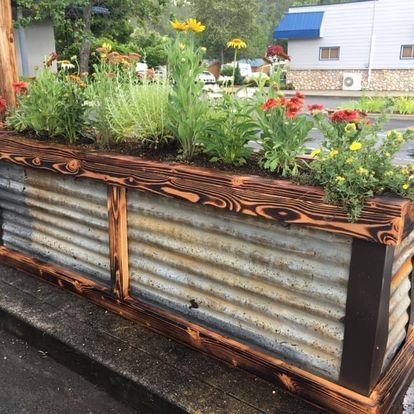 A planter made out of corrugated metal and wood with flowers in it