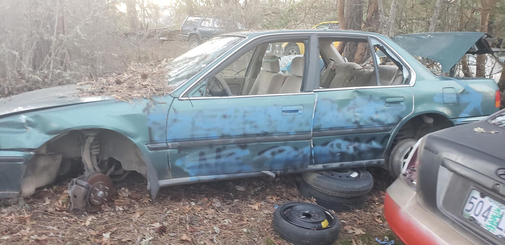 A blue car is sitting in a pile of leaves.