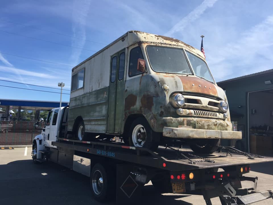 An old truck is being towed by a tow truck.