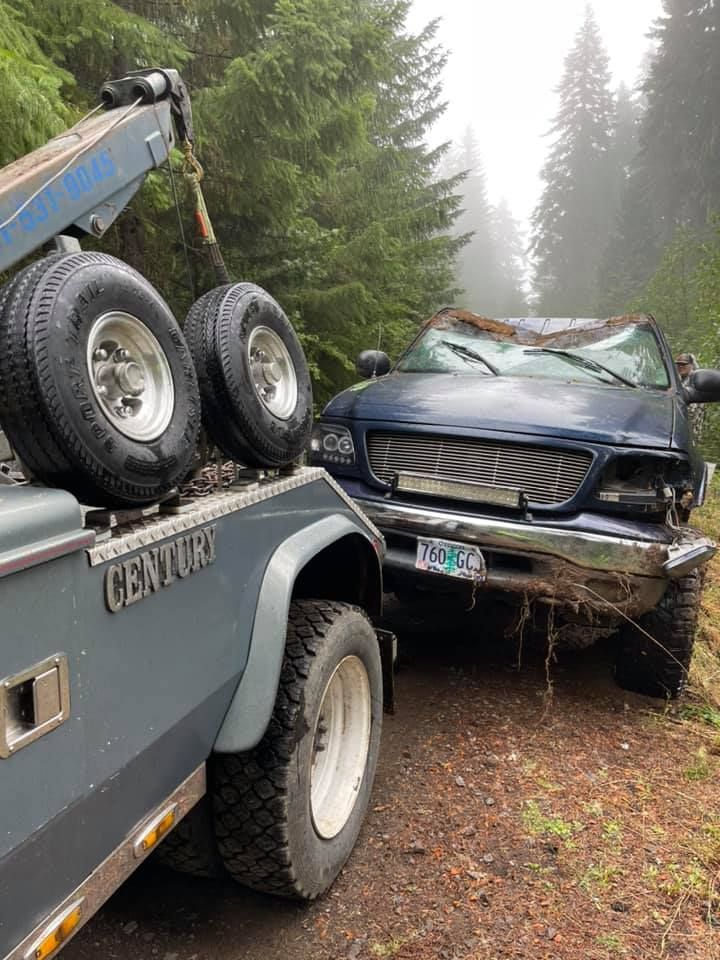 A tow truck is towing a car that has crashed into a tree.
