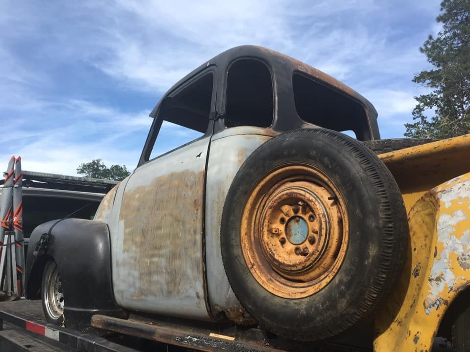 An old truck is sitting on top of a trailer.