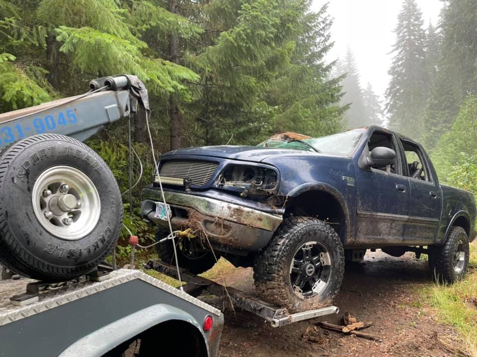 A blue truck is being towed by a tow truck.