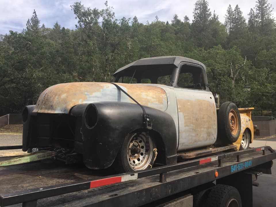 An old truck is sitting on top of a tow truck.