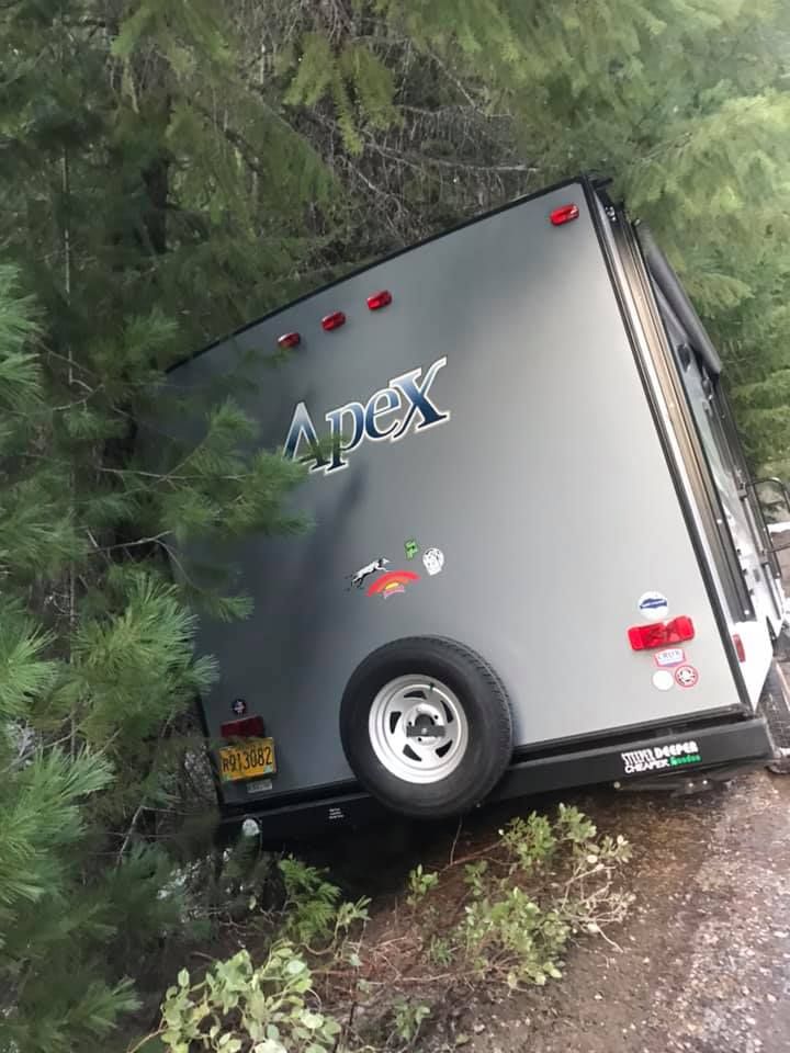 A grey apex trailer is stuck in the woods