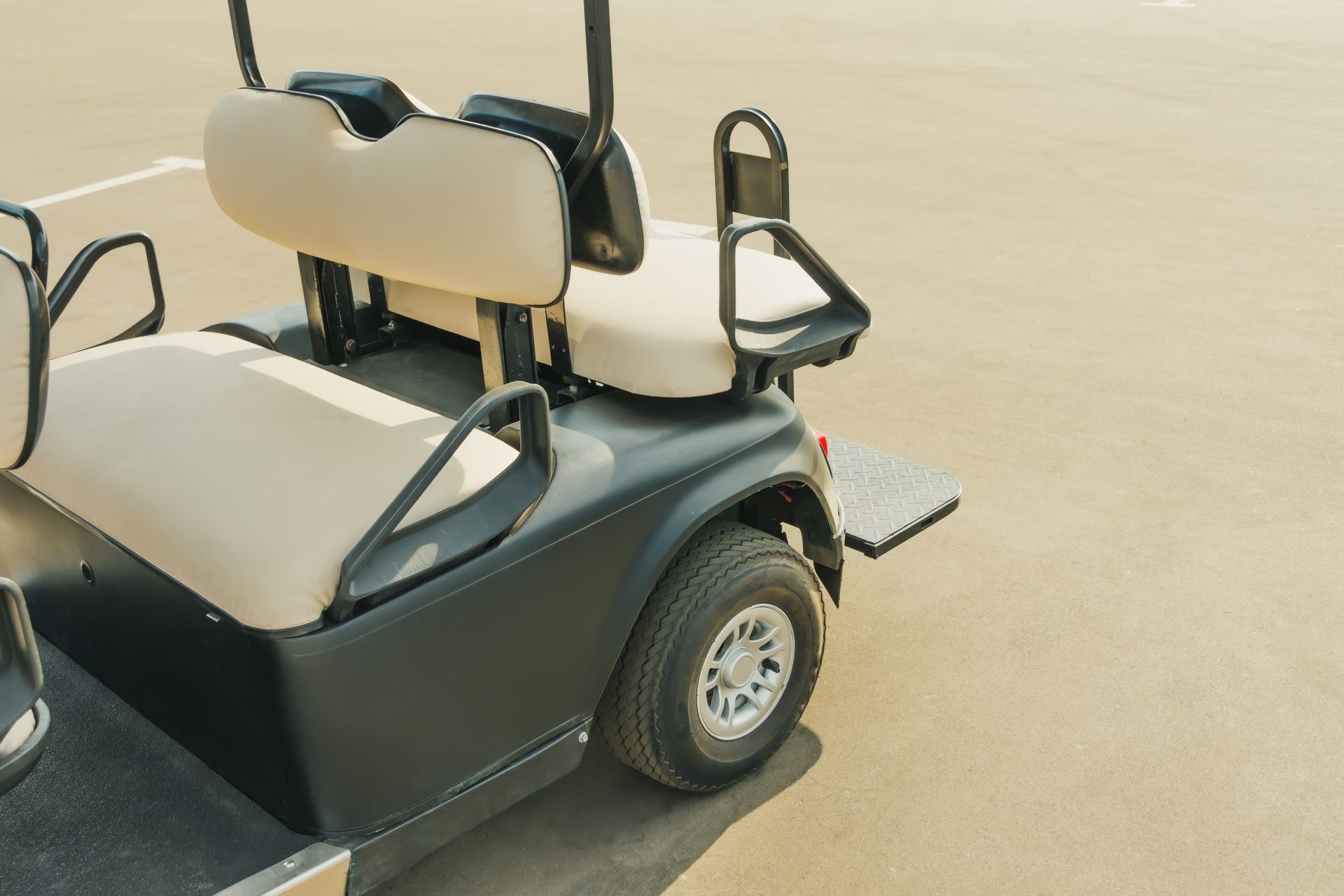 Empty golf cart parked on sandy ground in bright sunlight