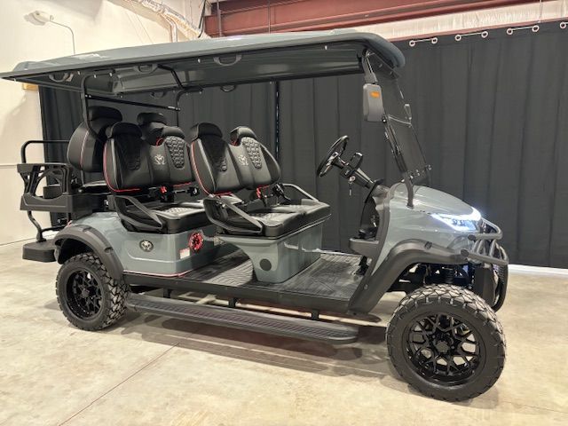 Gray four-seat golf cart with roof and off-road tires parked indoors.