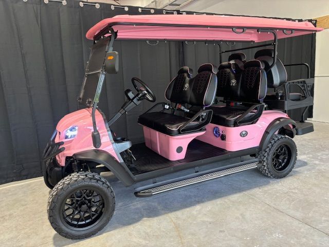 Pink four-seat golf cart with black trim, parked indoors on a concrete floor