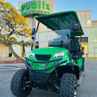 Green utility cart parked in front of a Publix supermarket entrance.