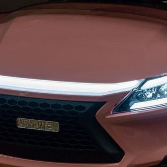 Front view of a copper car with a black grille and illuminated headlight