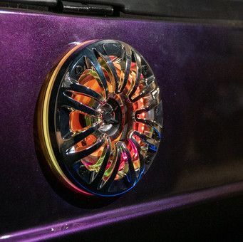 Chrome speaker grille with purple and gold accents on a dark purple surface