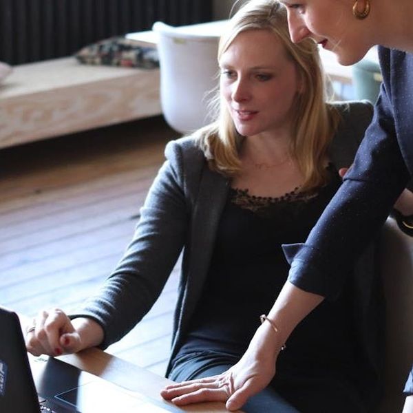 Twee vrouwen kijken naar een laptop en één heeft een ring aan haar vinger