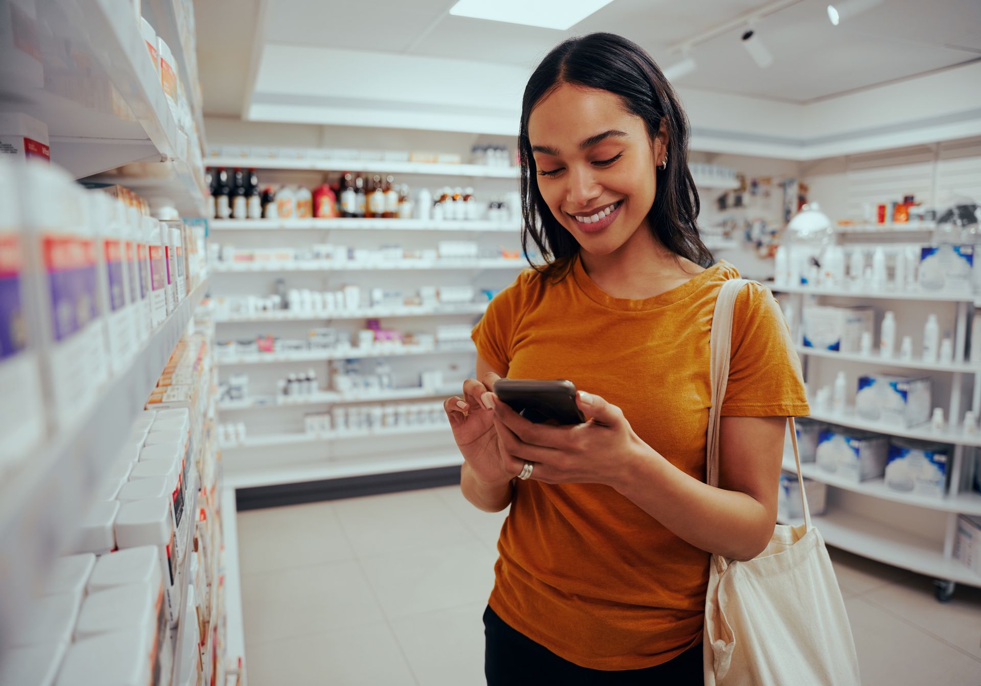 A woman is looking at her phone in a pharmacy