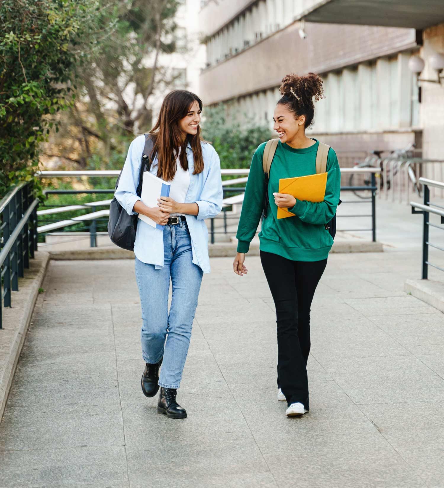 Two women are walking down a sidewalk holding hands