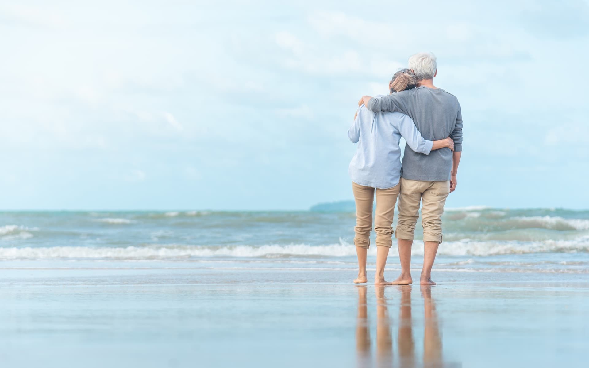 Two people hugging on the shore with a blue sky