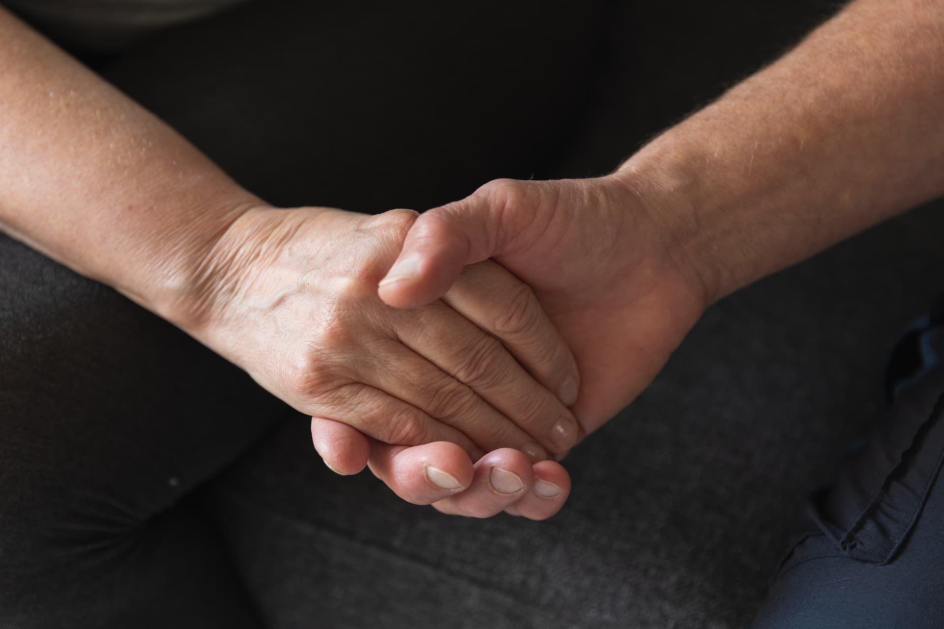 Two people holding hands against a black background